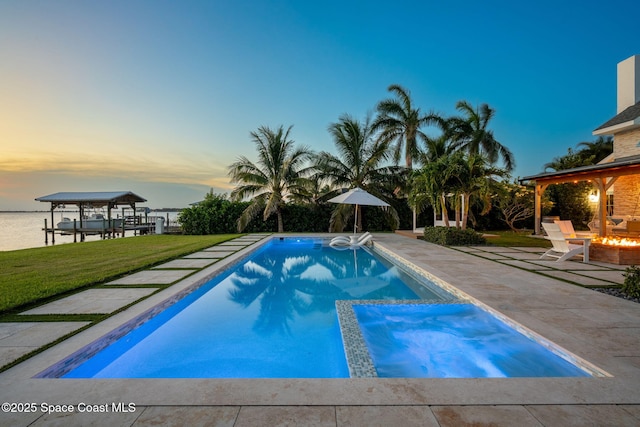 2600 N Riverside Dr, Indialantic, FL 32903 - pool at dusk with a patio, a lawn, a fire pit, and a pool with connected hot tub
