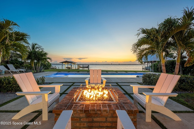 2600 N Riverside Dr, Indialantic, FL 32903 - patio terrace at dusk featuring a fire pit, an outdoor pool, a water view, and a patio area