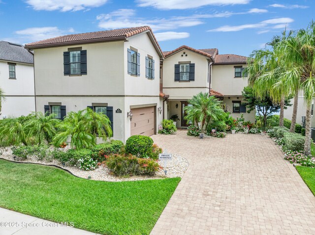 7873 Desmond Ave, Melbourne, FL 32940 - mediterranean / spanish-style house with an attached garage, a tiled roof, decorative driveway, and stucco siding