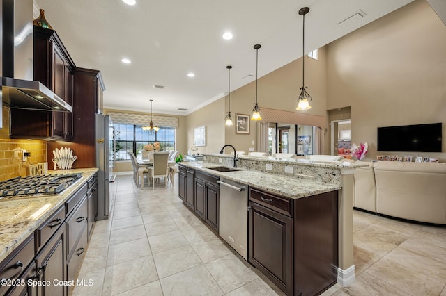 7873 Desmond Ave, Melbourne, FL 32940 - kitchen featuring wall chimney exhaust hood, stainless steel appliances, a chandelier, dark brown cabinetry, and open floor plan