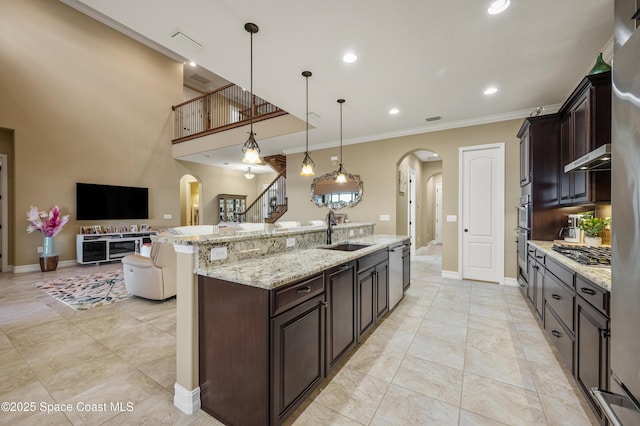 7873 Desmond Ave, Melbourne, FL 32940 - kitchen featuring arched walkways, open floor plan, appliances with stainless steel finishes, ornamental molding, and a center island with sink