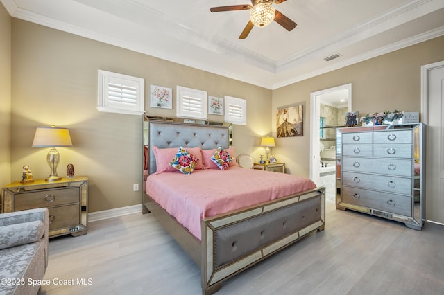 7873 Desmond Ave, Melbourne, FL 32940 - bedroom with light wood finished floors, ornamental molding, a raised ceiling, connected bathroom, and a ceiling fan