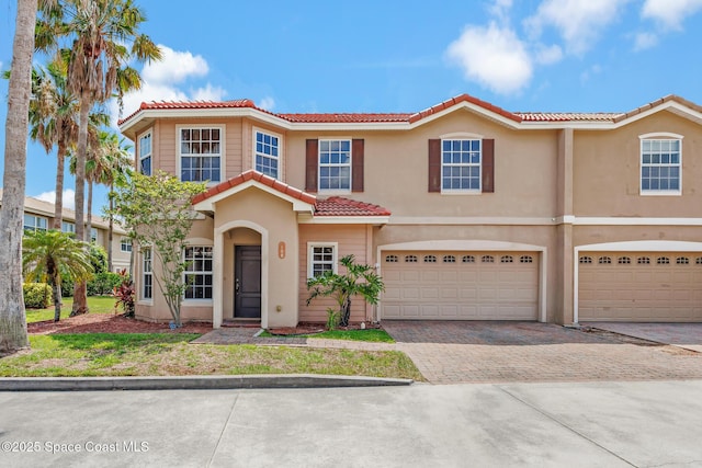 1375 Isabella Dr Unit 108, Melbourne, FL 32935 - view of front of house with a tile roof, decorative driveway, an attached garage, and stucco siding