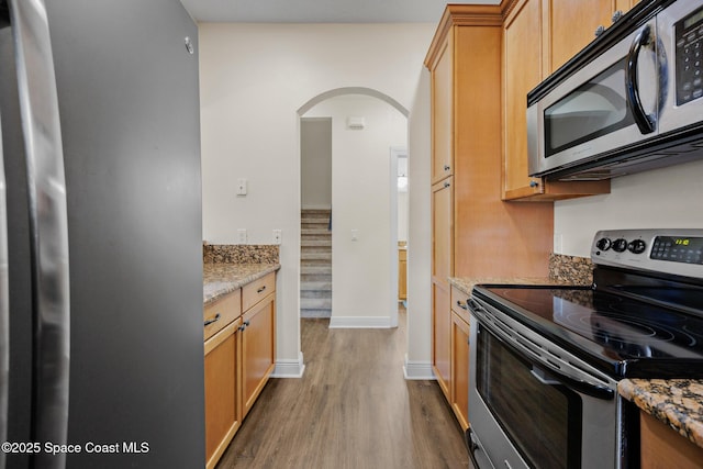 1375 Isabella Dr Unit 108, Melbourne, FL 32935 - kitchen featuring appliances with stainless steel finishes, arched walkways, wood finished floors, and light stone counters