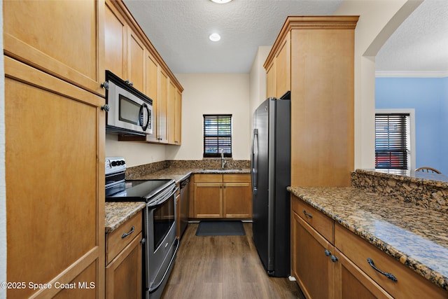 1375 Isabella Dr Unit 108, Melbourne, FL 32935 - kitchen featuring stainless steel appliances, a textured ceiling, dark wood finished floors, arched walkways, and stone counters