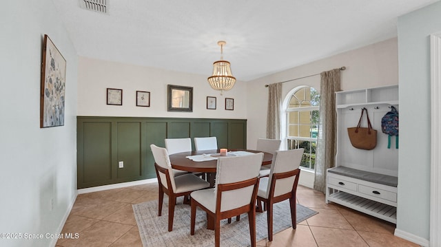 4060 Aria Dr, Melbourne, FL 32904 - dining room with a chandelier, light tile patterned floors, a decorative wall, and a wainscoted wall