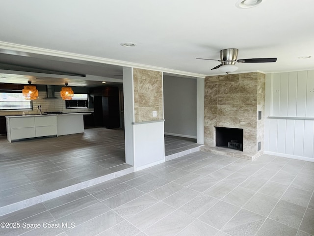 235 NE 2nd St, Satellite Beach, FL 32937 - unfurnished living room with light tile patterned floors, ornamental molding, a ceiling fan, and a fireplace