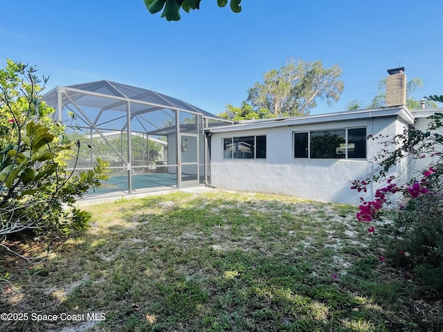 235 NE 2nd St, Satellite Beach, FL 32937 - back of property with stucco siding, a chimney, a lanai, a yard, and an outdoor pool