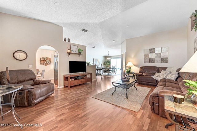 1137 White Oak Cir, Melbourne, FL 32934 - living room featuring a textured ceiling, arched walkways, and light wood finished floors