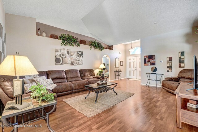 1137 White Oak Cir, Melbourne, FL 32934 - living room with wood finished floors, arched walkways, vaulted ceiling, and a textured ceiling