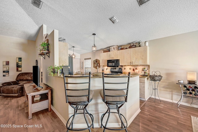 1137 White Oak Cir, Melbourne, FL 32934 - kitchen featuring black microwave, stove, light brown cabinetry, a textured ceiling, and a peninsula