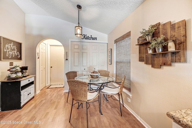 1137 White Oak Cir, Melbourne, FL 32934 - dining space with arched walkways, vaulted ceiling, light wood-style floors, and a textured ceiling