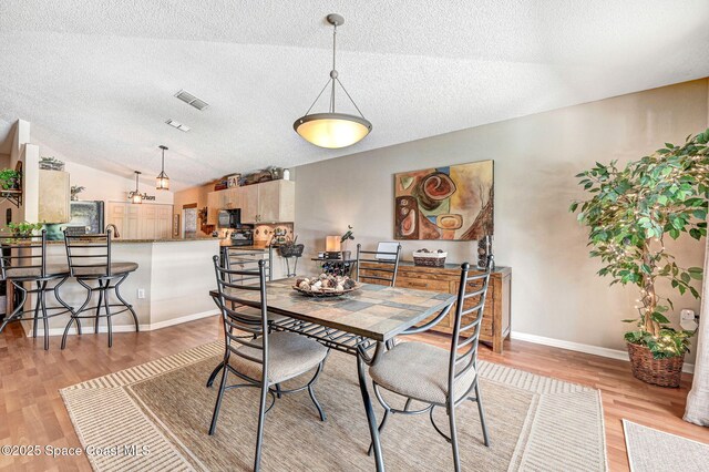1137 White Oak Cir, Melbourne, FL 32934 - dining area featuring a textured ceiling, light wood finished floors, and lofted ceiling