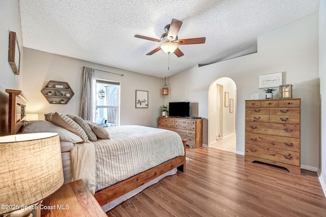 1137 White Oak Cir, Melbourne, FL 32934 - bedroom with arched walkways, a textured ceiling, light wood-style floors, ceiling fan, and vaulted ceiling