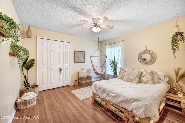 1137 White Oak Cir, Melbourne, FL 32934 - bedroom with a closet, a textured ceiling, wood finished floors, and a ceiling fan