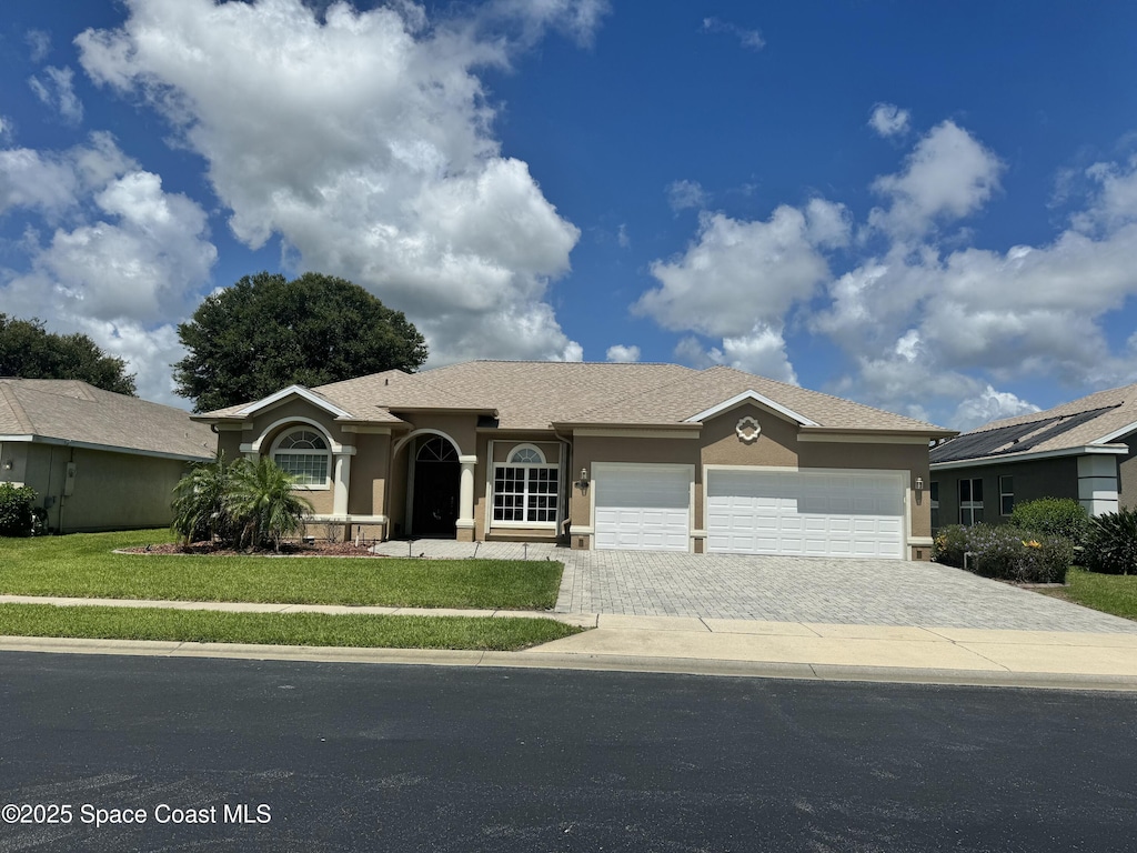 1351 Tamango Dr, Melbourne, FL 32904 - ranch-style home featuring stucco siding, an attached garage, a front yard, and decorative driveway