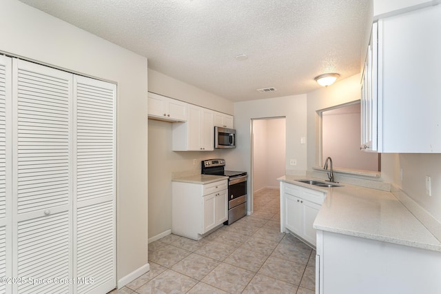 1337 Pakenham St NW, Palm Bay, FL 32907 - kitchen with appliances with stainless steel finishes, a textured ceiling, white cabinetry, and light tile patterned floors