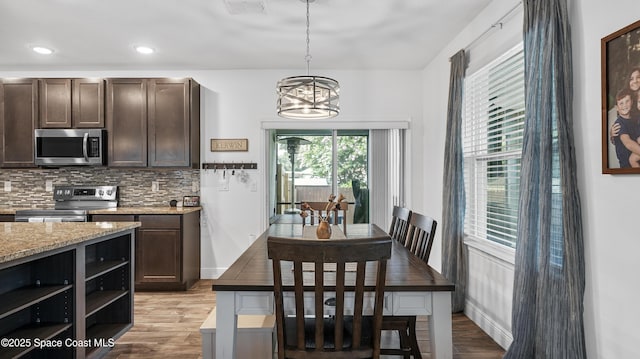 6830 Harp Ave, Cocoa, FL 32927 - kitchen with appliances with stainless steel finishes, dark brown cabinets, light wood-type flooring, backsplash, and a chandelier