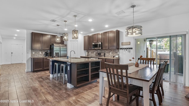 6830 Harp Ave, Cocoa, FL 32927 - kitchen with stainless steel appliances, dark brown cabinets, tasteful backsplash, recessed lighting, and a kitchen island with sink