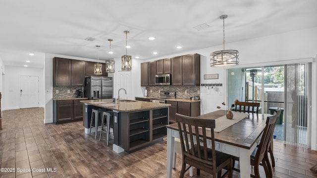 6830 Harp Ave, Cocoa, FL 32927 - kitchen with stainless steel appliances, dark brown cabinetry, backsplash, a chandelier, and dark wood-type flooring