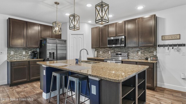 6830 Harp Ave, Cocoa, FL 32927 - kitchen featuring stainless steel appliances, light wood finished floors, dark brown cabinets, light stone countertops, and tasteful backsplash