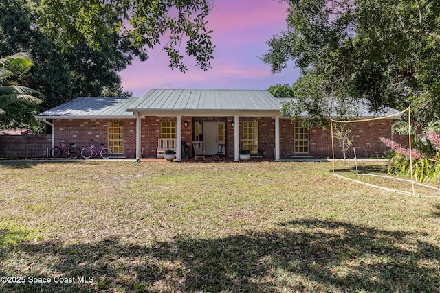 4685 Sand Point Rd, Grant, FL 32949 - rear view of property featuring a lawn, brick siding, a metal roof, and a porch