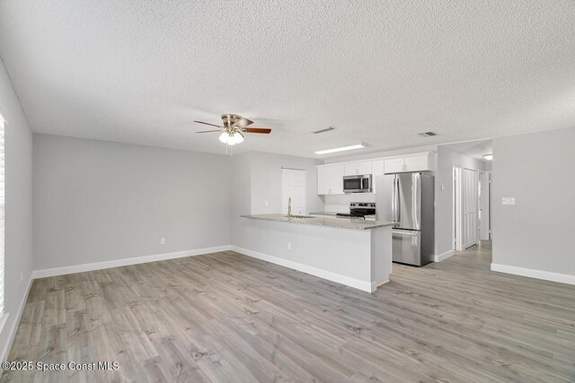 1256 16th Ave SW, Vero Beach, FL 32962 - kitchen featuring stainless steel appliances, ceiling fan, light wood finished floors, white cabinets, and a textured ceiling