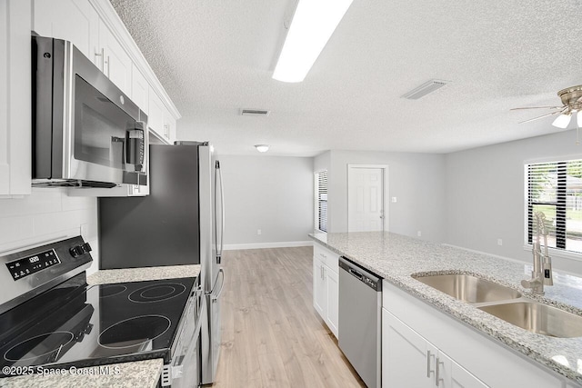 1256 16th Ave SW, Vero Beach, FL 32962 - kitchen featuring stainless steel appliances, light wood-type flooring, a textured ceiling, white cabinets, and a ceiling fan