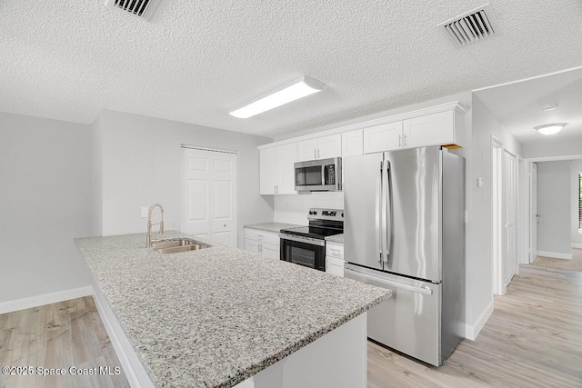 1256 16th Ave SW, Vero Beach, FL 32962 - kitchen featuring appliances with stainless steel finishes, white cabinetry, light wood-style floors, tasteful backsplash, and light stone countertops