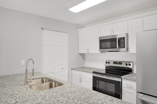 1256 16th Ave SW, Vero Beach, FL 32962 - kitchen featuring stainless steel appliances, backsplash, white cabinetry, light stone countertops, and a textured ceiling