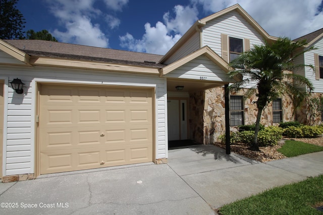 9027 Manchester Ln Unit 22F, West Melbourne, FL 32904 - view of front of house featuring driveway, stone siding, and an attached garage