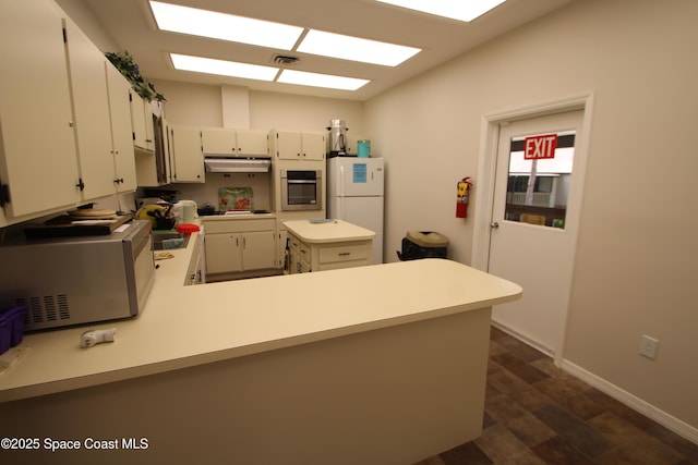 9027 Manchester Ln Unit 22F, West Melbourne, FL 32904 - kitchen with appliances with stainless steel finishes, under cabinet range hood, light countertops, a peninsula, and white cabinets