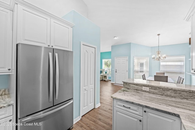 2690 Camberly Cir, Melbourne, FL 32940 - kitchen featuring freestanding refrigerator, light wood-style flooring, a chandelier, white cabinets, and decorative light fixtures