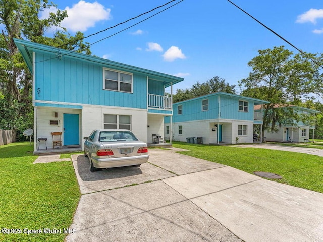51,55,59 E 32nd Street, Jacksonville, FL 32208 - view of front of property with driveway, a balcony, board and batten siding, and a front lawn