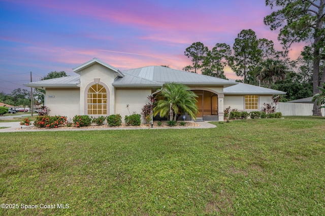 7045 Grissom Pkwy, Cocoa, FL 32927 - ranch-style home featuring a metal roof, a front yard, stucco siding, and a sunroom