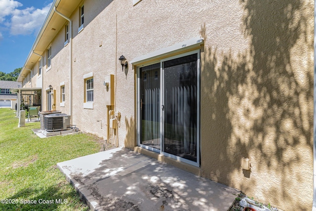 609 Cedar Side Cir NE, Palm Bay, FL 32905 - view of exterior entry with a patio area, stucco siding, and a lawn