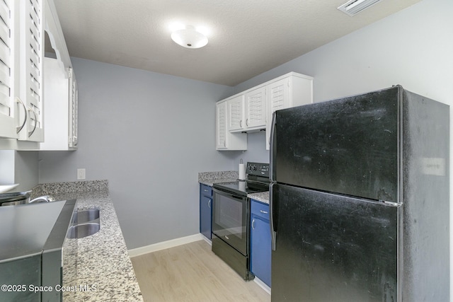 583 Mandan Ave, Melbourne, FL 32935 - kitchen with black appliances, light wood-style flooring, blue cabinetry, white cabinetry, and light stone countertops