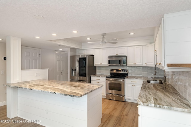 1708 Atlantic St Unit 4F, Melbourne Beach, FL 32951 - kitchen featuring stainless steel appliances, light wood-style floors, white cabinets, a textured ceiling, and backsplash