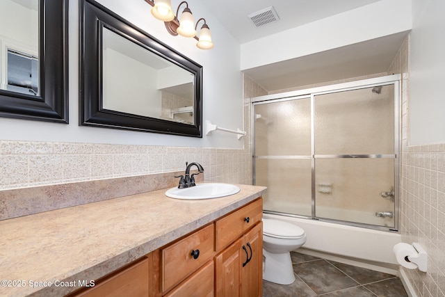 1708 Atlantic St Unit 4F, Melbourne Beach, FL 32951 - bathroom featuring tile walls, vanity, tile patterned floors, bath / shower combo with glass door, and a wainscoted wall