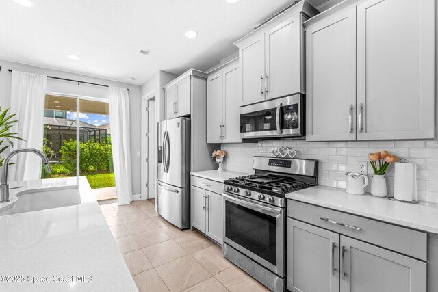 3089 Ribbon Grass Dr, Melbourne, FL 32940 - kitchen featuring appliances with stainless steel finishes, decorative backsplash, light tile patterned floors, gray cabinets, and recessed lighting