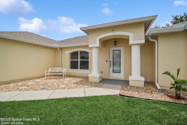 183 Frante Ave NE, Palm Bay, FL 32907 - doorway to property with stucco siding, a shingled roof, and a yard
