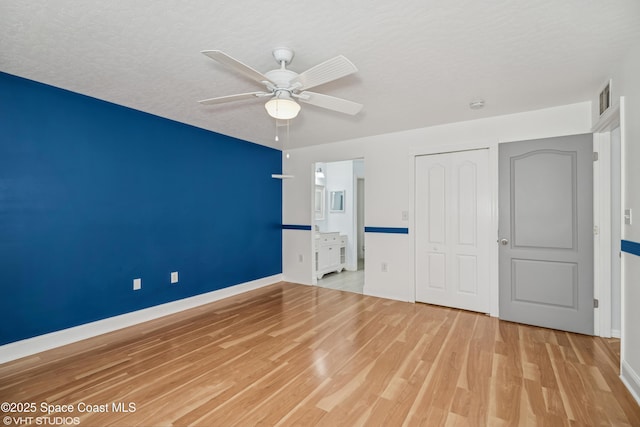183 Frante Ave NE, Palm Bay, FL 32907 - unfurnished bedroom with wood finished floors, a closet, a ceiling fan, a textured ceiling, and connected bathroom