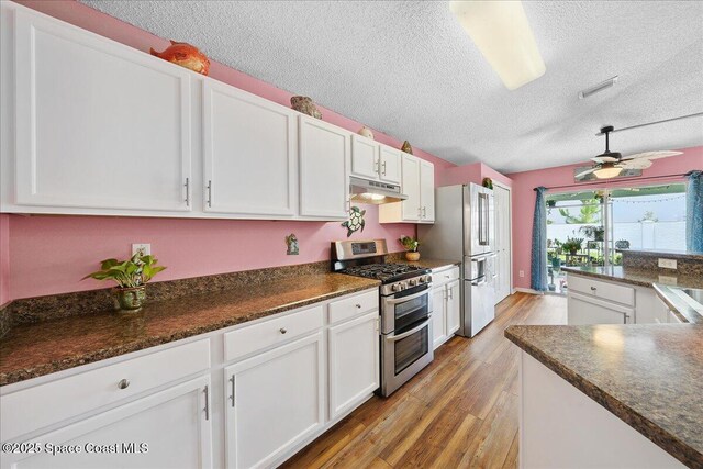 2627 Deercroft Dr, Melbourne, FL 32940 - kitchen featuring appliances with stainless steel finishes, under cabinet range hood, a textured ceiling, light wood-style floors, and white cabinets