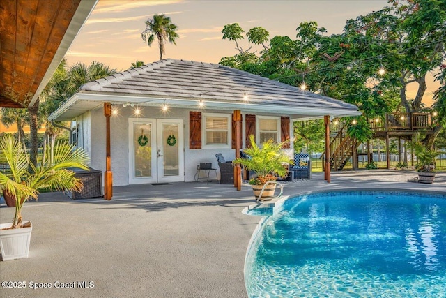 260 Utopia Cir, Merritt Island, FL 32952 - pool at dusk featuring an outdoor pool, french doors, stairs, an outdoor structure, and a patio
