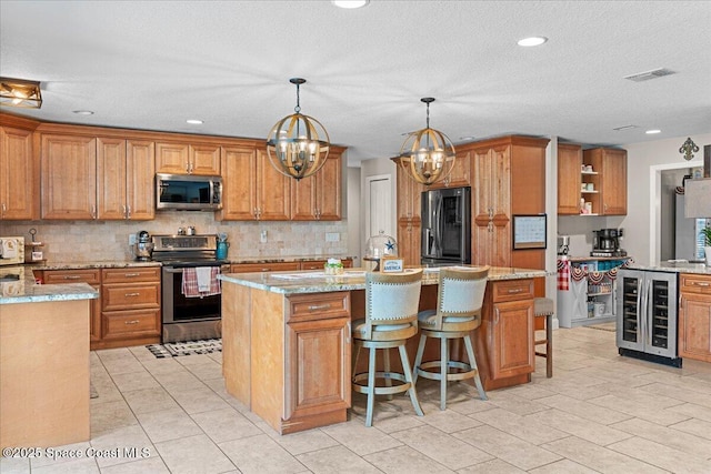 260 Utopia Cir, Merritt Island, FL 32952 - kitchen featuring wine cooler, stainless steel appliances, a chandelier, backsplash, and brown cabinets