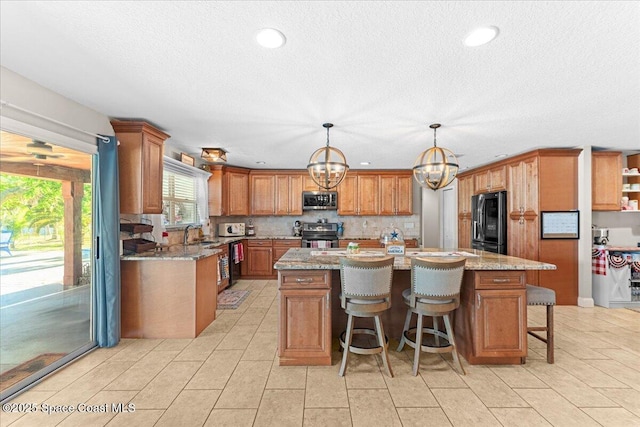 260 Utopia Cir, Merritt Island, FL 32952 - kitchen with appliances with stainless steel finishes, a center island, a textured ceiling, a chandelier, and brown cabinets