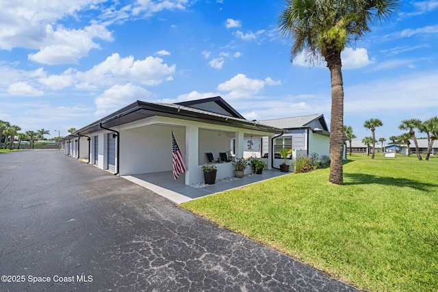743 Palm Springs Cir, Satellite Beach, FL 32937 - view of side of home with a lawn, stucco siding, covered porch, and asphalt driveway