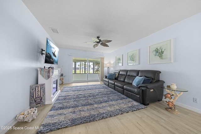 743 Palm Springs Cir, Satellite Beach, FL 32937 - living room featuring wood finished floors, a ceiling fan, and a glass covered fireplace