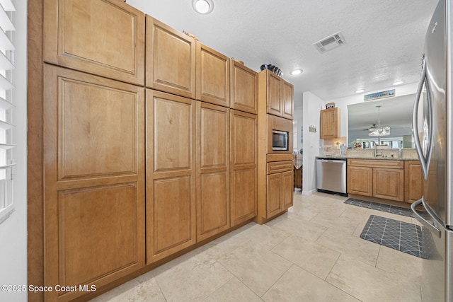 743 Palm Springs Cir, Satellite Beach, FL 32937 - kitchen featuring appliances with stainless steel finishes, brown cabinets, recessed lighting, a chandelier, and a textured ceiling
