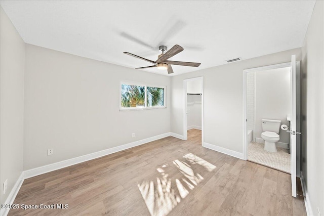 203 6th Ave Unit 9, Melbourne Beach, FL 32951 - unfurnished bedroom with wood finished floors, a spacious closet, ensuite bath, a closet, and a ceiling fan